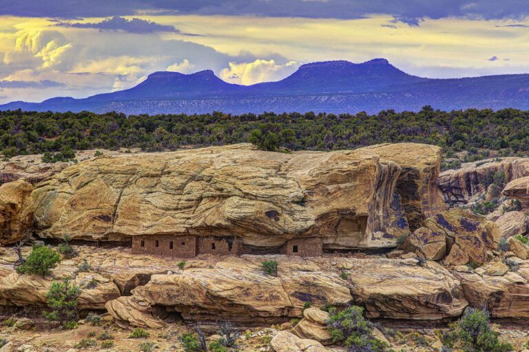 The Bears Ears buttes rise above a cliff dwelling on a sandstone ledge